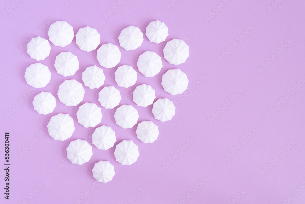 White meringues form a heart shape on a pink background, copy space. White meringues form a heart shape on a pink background, copy space.