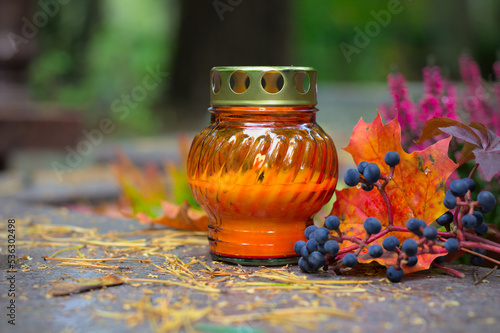 Obraz na plátně An orange candle on a grave in a cemetery on an autumn day