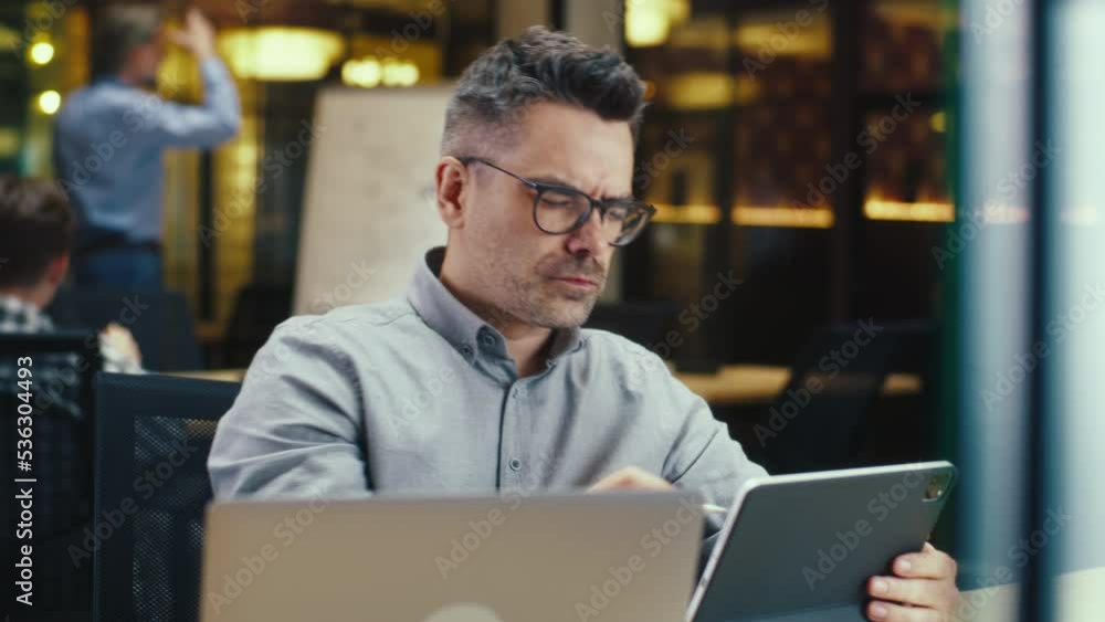 Male office worker, using tablet computer and digital pencil, working in modern office on startup project, business strategy or design of website. Work in IT company Male office worker, using tablet computer and digital pencil, working in modern office on startup project, business strategy or design of website. Work in IT company