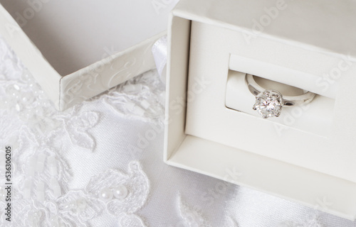 Engagement golden ring with diamond in a gift box on white wedding fabri photo