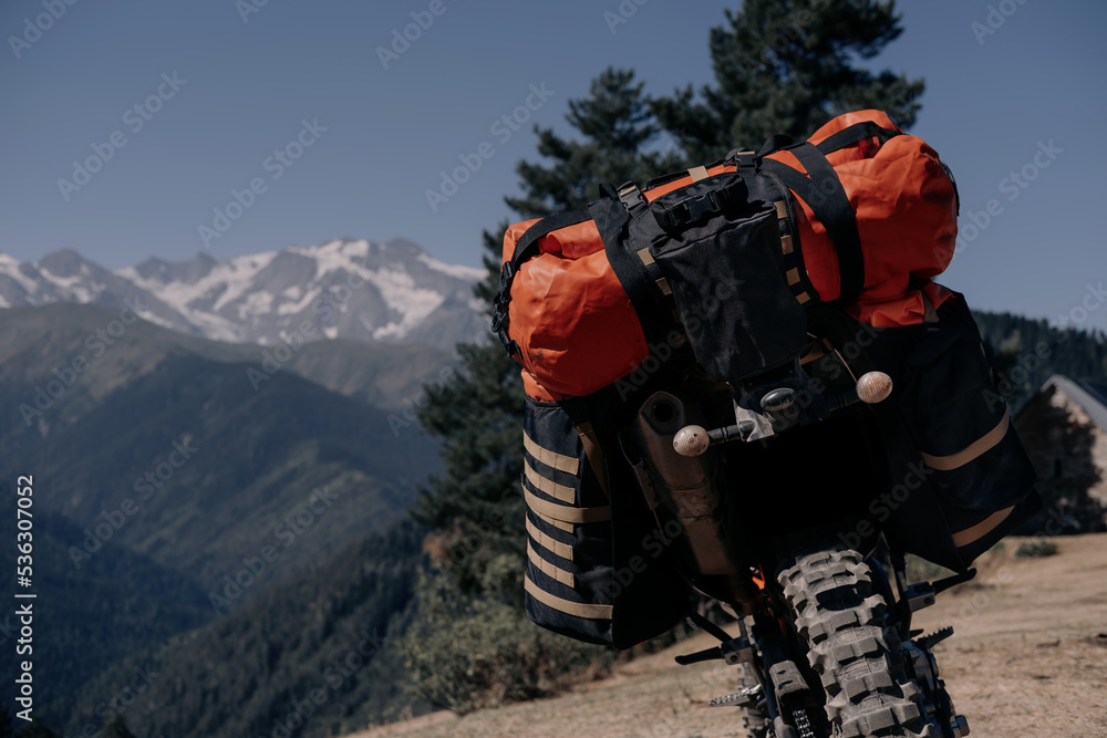 off-road motorcycle with dirt tires packed with dry bags and things for a long-distance motorcycle journey standing against the backdrop of a beautiful mountain landscape