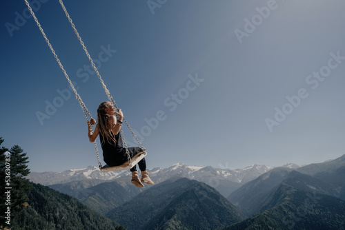 Dream and travel concept, Young beautiful female enjoying on swing flying in the sky over amazing mountain landscape