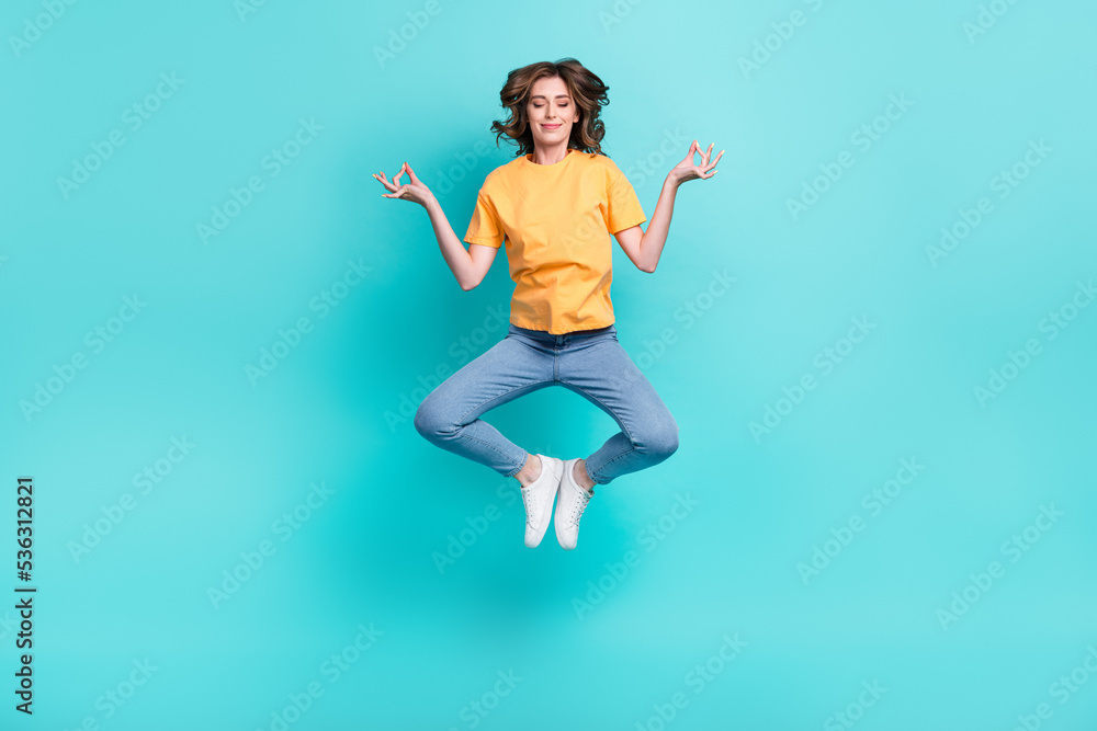Full length photo of dreamy sweet girl dressed yellow t-shirt jumping high enjoying yoga isolated teal color background