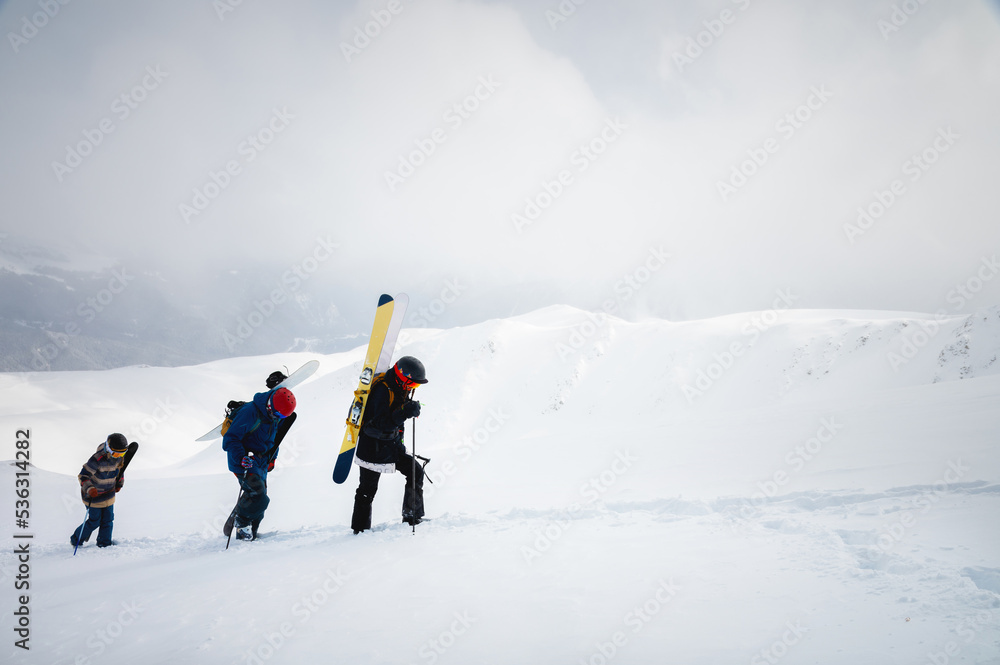 group of three backcountry skiers ascending a snowy mountainside on a beautiful foggy snowy day