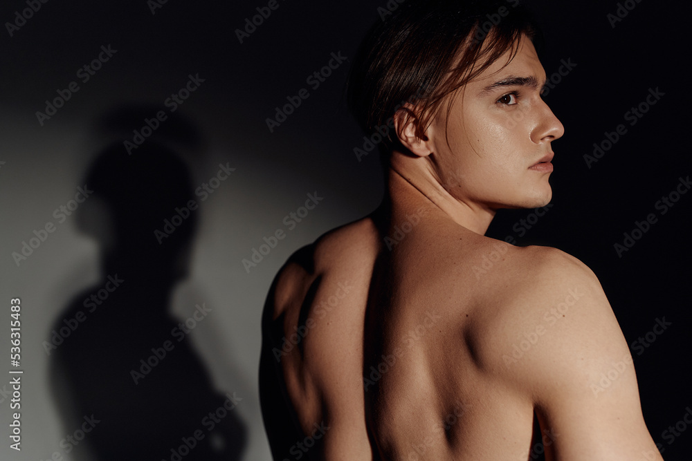 young shirtless man looking away on black and grey background. young shirtless man looking away on black and grey background.