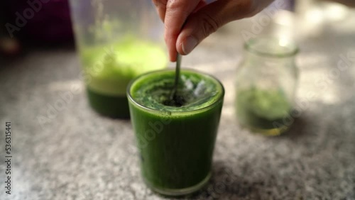 Adding Spirulina To Glass Of Healthy Green Vegetable Juice In The Kitchen. close up
