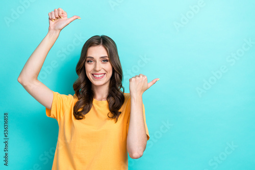 Photo of young pretty gorgeous nice cute girl student wear orange t-shirt toothy smile finger point empty space promoter isolated on cyan color background
