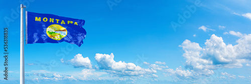 Montana - state of USA, flag waving on a blue sky in beautiful clouds - Horizontal banner
 photo