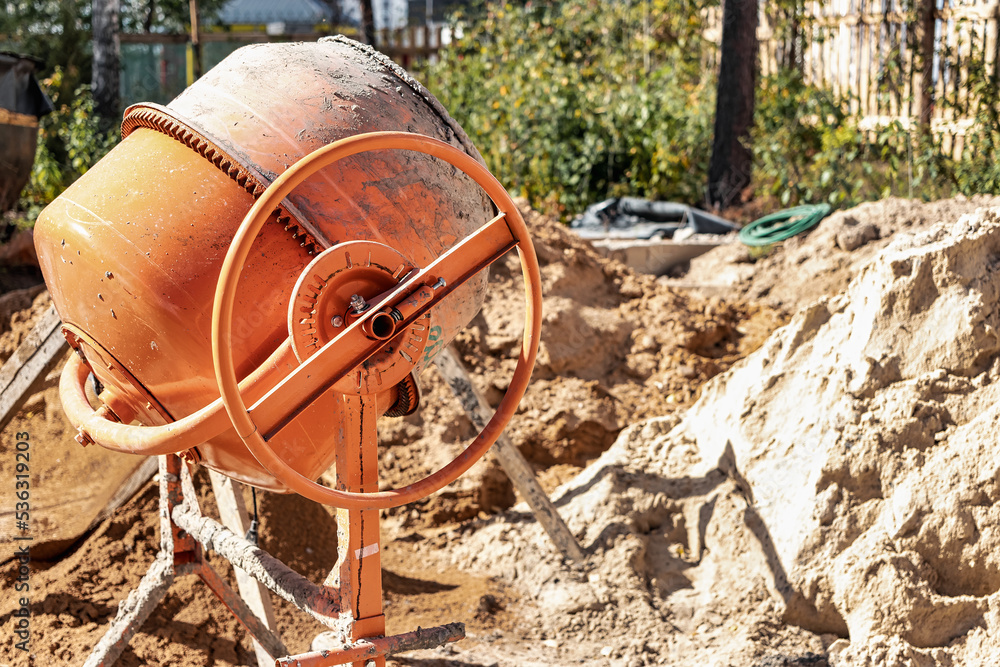 Industrial concrete mixer at a construction site. Mixing concrete and mortar on site. Construction equipment. Industrial concrete mixer at a construction site. Mixing concrete and mortar on site. Construction equipment.