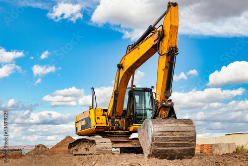Powerful excavator at a construction site against a blue cloudy sky. Earthmoving equipment for construction. Development and movement of soil.