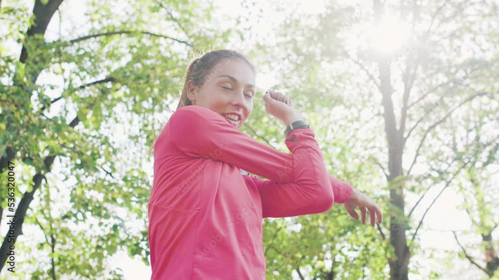 Fitness girl stretching her arms and neck in the park. Warming up exercise before running Fitness girl stretching her arms and neck in the park. Warming up exercise before running