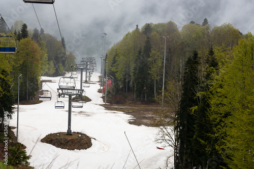 Empty chairlift in ski resort. Shot in summer with green grass and very little snow toned photo