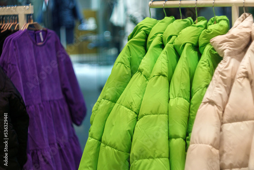 Winter colored jackets and vests on the stands in the sports store. Selective focus