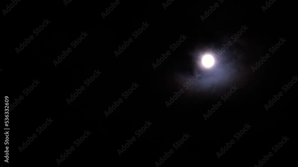 Magical full moon at night. Telephoto view of mysterious clouds flying against the bright full moon. Real midnight footage with black background and copy space. Creepy halloween sky, astrology concept Magical full moon at night. Telephoto view of mysterious clouds flying against the bright full moon. Real midnight footage with black background and copy space. Creepy halloween sky, astrology concept