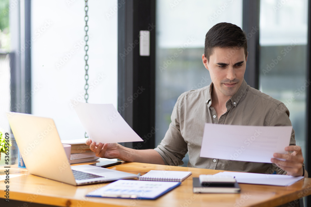 Handsome young businessman in the office serious about work analyzing documents and planning financial accounts. Handsome young businessman in the office serious about work analyzing documents and planning financial accounts.