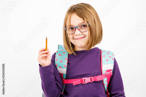 Dziewczynka z tornistrem i ołówkiem w dłoni planuje nowy rok, nowy rozdział, postanowienia noworoczne, dziecko w okularach, pierwszoklasista, zadowolony, edukacja, tornister, ołówek, mały uczeń