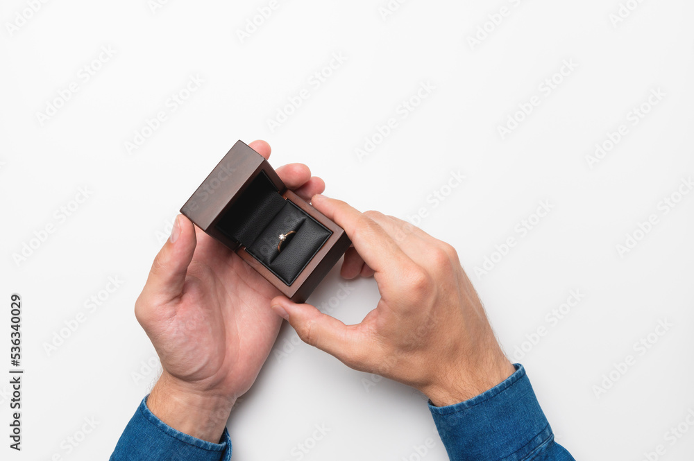 a man's hand holds a diamond engagement ring in a wooden elegant box, making a marriage proposal a man's hand holds a diamond engagement ring in a wooden elegant box, making a marriage proposal