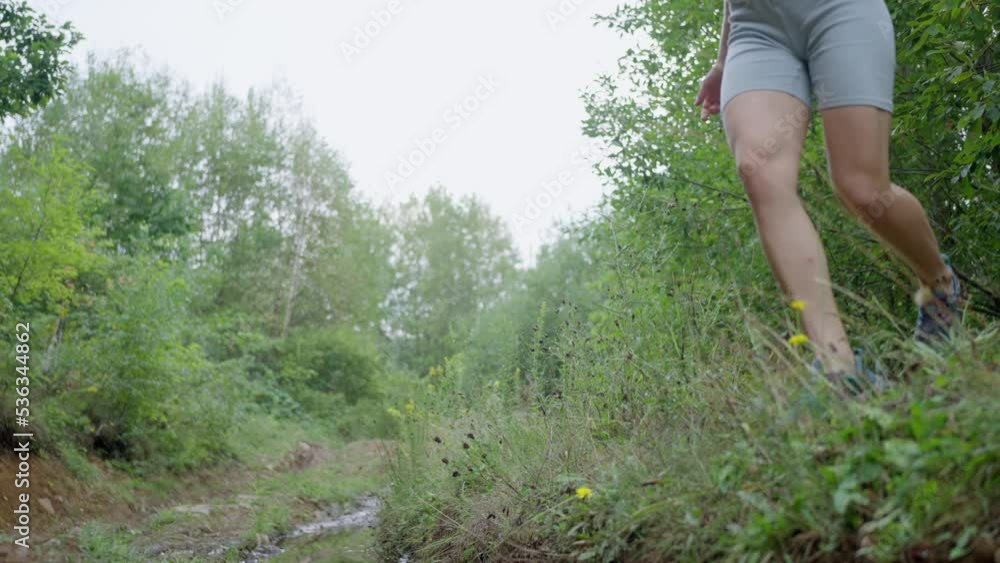 Female legs crossing river water flowing on stones in mountain. Barefoot woman running and jumping over rocky river stream on hot sunny day. Rocky watercourse in summer forest. slow motion Female legs crossing river water flowing on stones in mountain. Barefoot woman running and jumping over rocky river stream on hot sunny day. Rocky watercourse in summer forest. slow motion