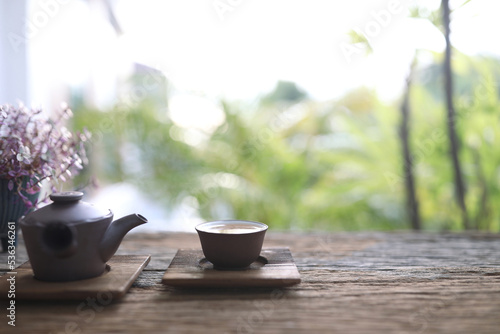 Earthenware tea pot and cup on wooden table outdoor chill relaxing view