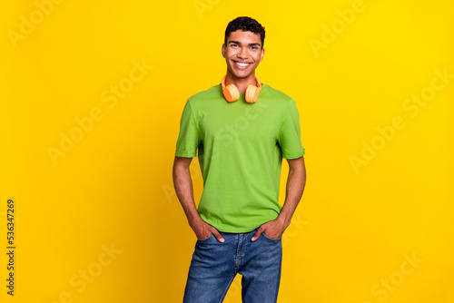 Portrait photo of young attractive handsome confident man hold hands pocket denim wear nice expensive wireless headphones isolated on yellow color background