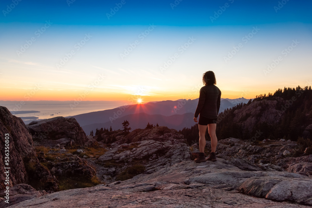 Adventurous Woman Hiker on top of Canadian Mountain Landscape. Sunny Sunset Sky. Top of Mt Seymour near Vancouver, British Columbia, Canada. Adventure Travel Concept