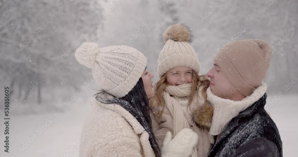Playful happy parents with daughter in winter forest