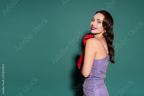 charming young woman in red gloves and purple dress smiling on green background. © LIGHTFIELD STUDIOS