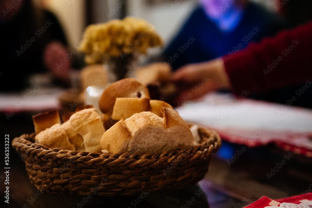 Bites of fresh white bread in a basket on a table in a restaurant. People on background