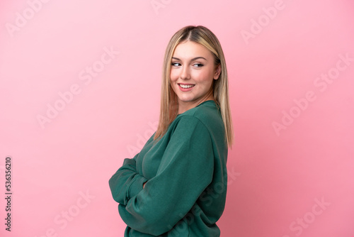 Young caucasian woman isolated on pink background with arms crossed and happy © luismolinero