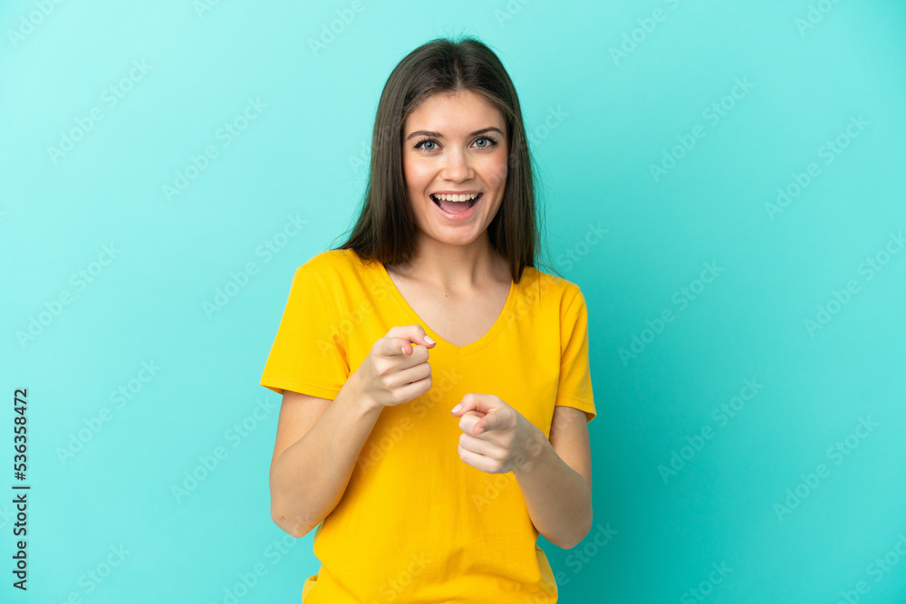Young caucasian woman isolated on blue background surprised and pointing front Young caucasian woman isolated on blue background surprised and pointing front