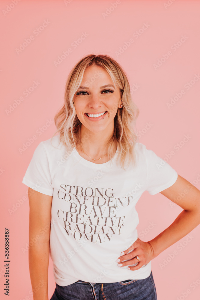 Obraz premium Woman stands confidently against pink backdrop looking at camera