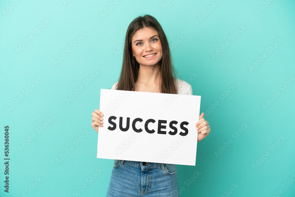 Young caucasian woman isolated on blue background holding a placard with text SUCCESS with happy expression Young caucasian woman isolated on blue background holding a placard with text SUCCESS with happy expression