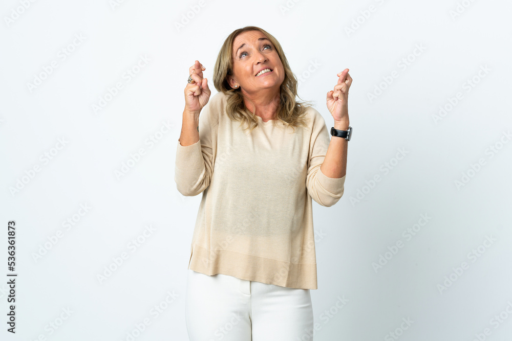 Middle aged blonde woman over isolated white background with fingers crossing Middle aged blonde woman over isolated white background with fingers crossing