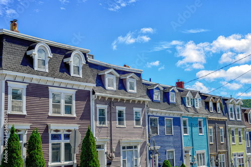 Multiple colorful wooden historic residential Second Empire style buildings attached with mansard roofs and arched and curved dormers on Cochrane Street in St. John's, Newfoundland. 