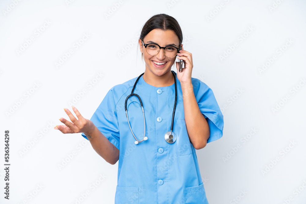 Young nurse woman isolated on white background keeping a conversation with the mobile phone with someone
