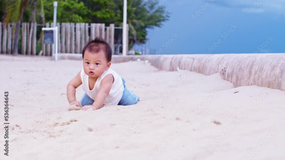 Healthy asian baby toddler crawling on the beach to learn to crawl outdoors. Adorable baby keeping her belly and legs down on sand to belly crawl fun and happiness at home. Baby growth concept Healthy asian baby toddler crawling on the beach to learn to crawl outdoors. Adorable baby keeping her belly and legs down on sand to belly crawl fun and happiness at home. Baby growth concept