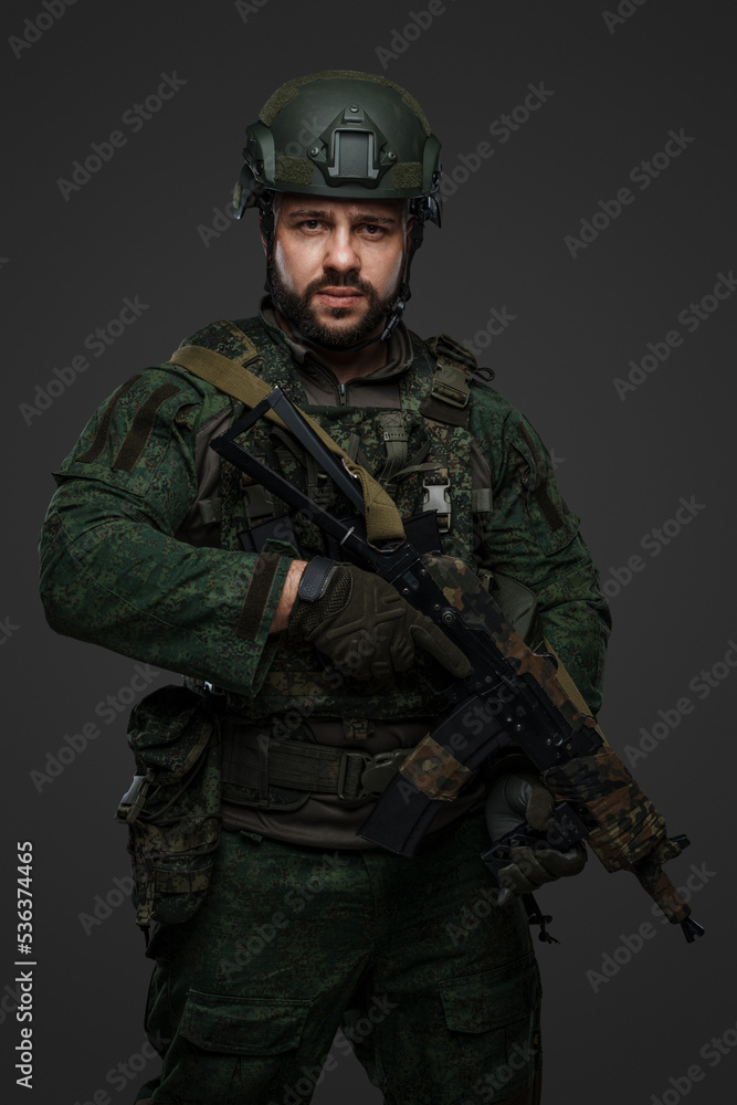 Studio shot of modern russian soldier dressed in camouflage uniform holding rifle.