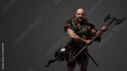 Portrait of aggressive scandinavian warrior with fur holding huge axe.