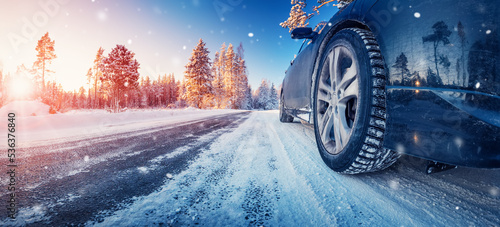 Closeup view of the car's wheel on the snowy road in natural park