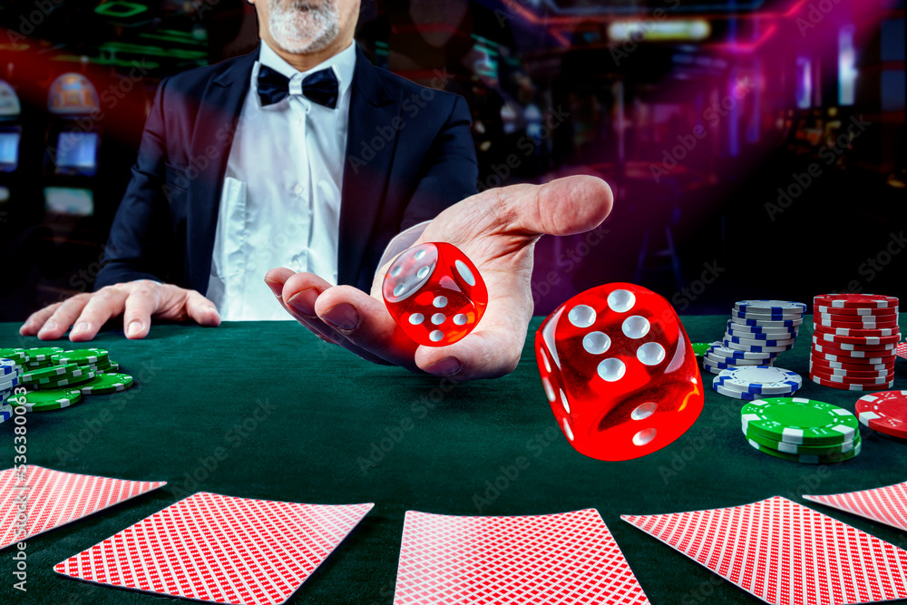 Stockfoto med beskrivningen Gambling concept. Close up of male hand throwing dice at casino, gambling club. Сasino chips or Casino tokens, poker cards, gambling man spending time in games of chance |