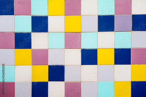 tiled background of yellow, bluew and pink squares, geometric pattern © Alberto
