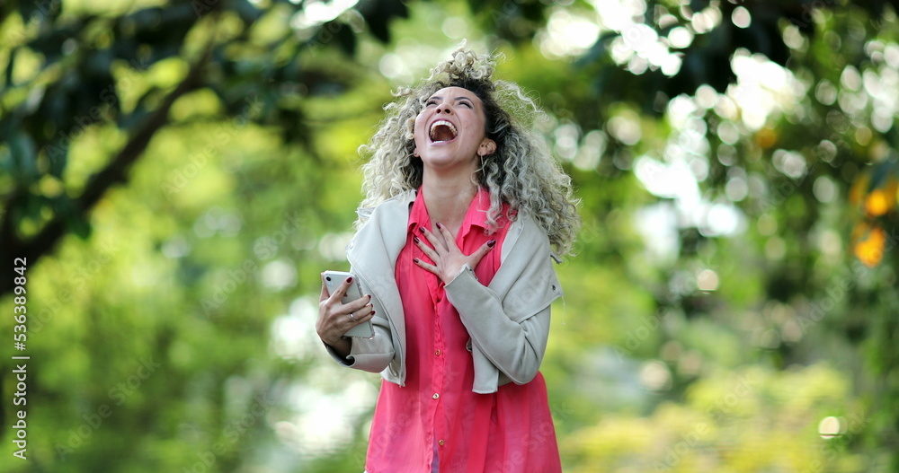 Hispanic woman jumping with joy celebrating success smartphone message Hispanic woman jumping with joy celebrating success smartphone message