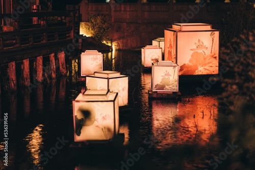 Group of floating Japanese square led lanterns in the pond at night photo