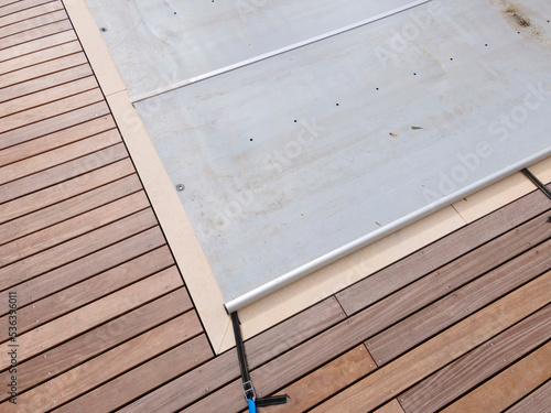 Drone photo of pool which is covered with grey pool tarpaulin, cover and prepared for winter and a garden with house