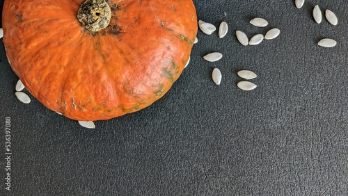 Orange pumpkin on a dark background with seeds