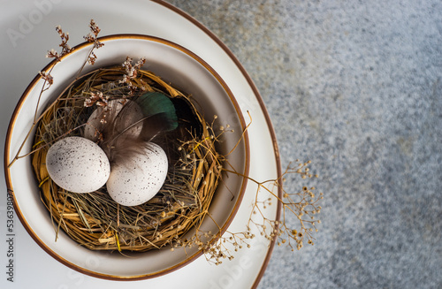Overhead view of an Easter place setting with a bird's nest and painted easter eggs photo