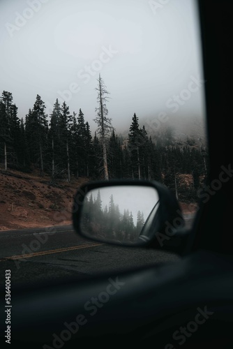 View from a car of fog on a road under pikes peak mountains trees in Colorado, vertical shot
