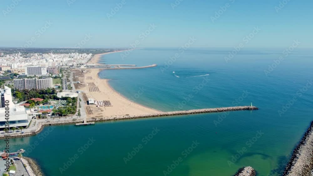Praia de Vilamoura, perspective from above. Drone ascending creating a beautiful panorama of the beach and city. Travel destination in South of Portugal, with luxury hotels and urbanisations. Praia de Vilamoura, perspective from above. Drone ascending creating a beautiful panorama of the beach and city. Travel destination in South of Portugal, with luxury hotels and urbanisations.
