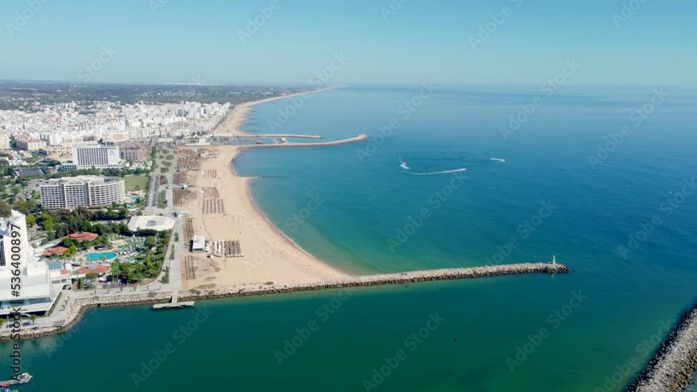 Praia de Vilamoura, perspective from above. Drone ascending creating a beautiful panorama of the beach and city. Travel destination in South of Portugal, with luxury hotels and urbanisations. Praia de Vilamoura, perspective from above. Drone ascending creating a beautiful panorama of the beach and city. Travel destination in South of Portugal, with luxury hotels and urbanisations.