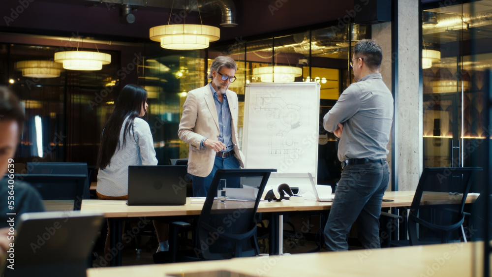 Diverse office workers having meeting, discussing blueprint on flipchart. Presentation of engineering architect startup in modern office of company. Businessman leading conference with managers Diverse office workers having meeting, discussing blueprint on flipchart. Presentation of engineering architect startup in modern office of company. Businessman leading conference with managers